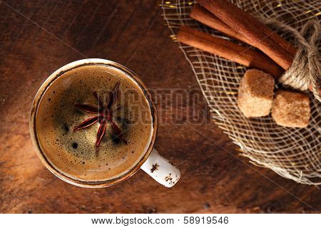 A cup of spiced coffee with anis star and cinamon sticks and sugar