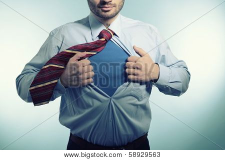 Super hero. Business man opening his shirt like a superhero, over blue background