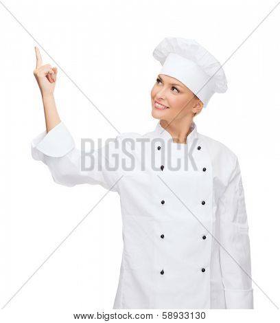 cooking, advertisement and food concept - smiling female chef, cook or baker pointing finger up to something