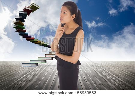 Thoughtful businesswoman against book steps against sky