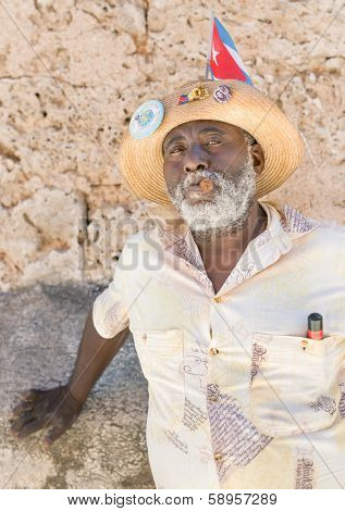 HAVANA,CUBA - JANUARY 20, 2014:Black man smoking a cuban cigar next to Cathedral Square.Characters like this are common in Old Havana and a photo opportunity for the growing number of foreign tourists