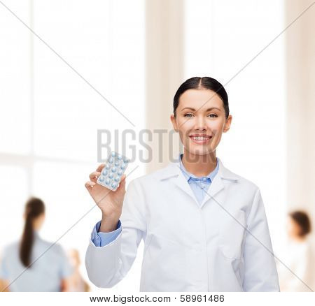 healthcare, medicine and pharmacy concept - smiling female doctor and with pills