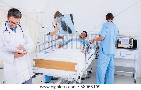Doctors holding reports by patient in bed at the hospital