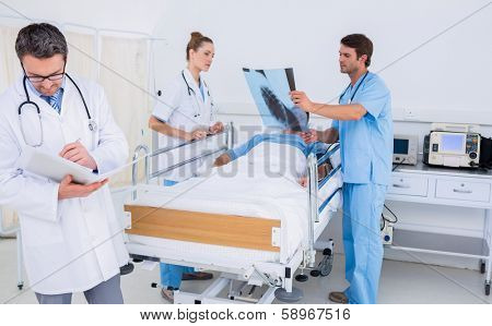 Doctors holding reports by patient in bed at the hospital