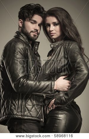 young casual couple standing embraced and looking at the camera in studio
