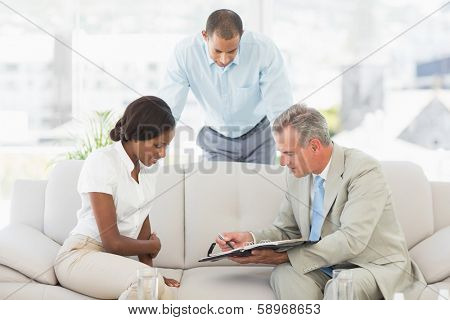 Salesman showing client where to sign the paperwork in the office