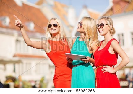 holidays and tourism concept - beautiful blonde girls toursits looking into tablet pc in the city