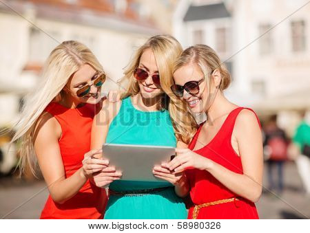 holidays and tourism concept - beautiful blonde girls toursits looking into tablet pc in the city