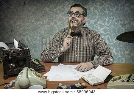 Pensive office employee with a pencil in his mouth looking up in the 1960s