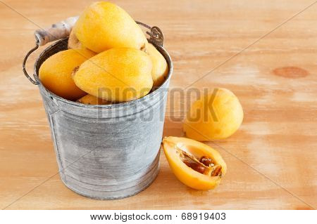 Loquat Fruit  In Bucket On Wooden Table