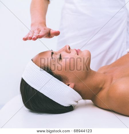 Peaceful brunette getting reiki therapy in the health spa