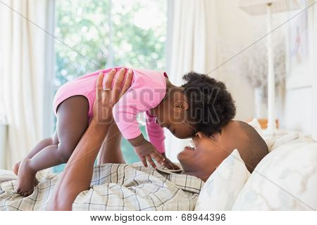 Father and baby girl lying on bed together at home in the bedroom