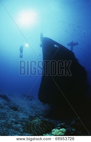 Underwater shoot of female scuba diver exploring sunken ship