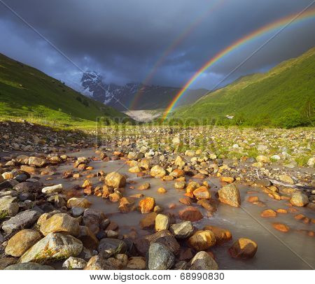 Summer landscape with a rainbow in the mountains above the river. Zemo Svaneti, Georgia