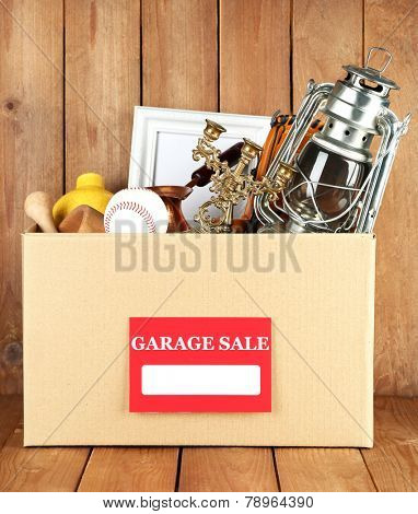 Box of unwanted stuff ready for a garage sale on wooden background