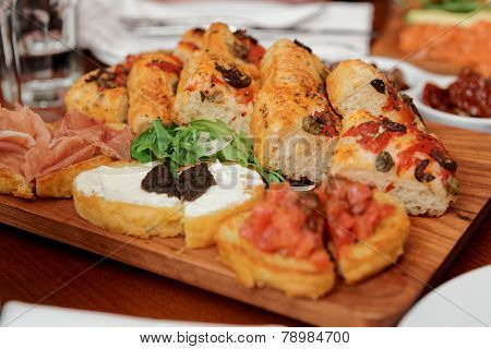 Italian appetizers on wooden plank, close-up
