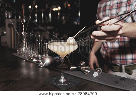Bartender is making a cocktail with leechee, toned image