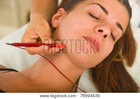 Attractive female patient receiving electro acupuncture on face as part of a anti-aging beauty treatment