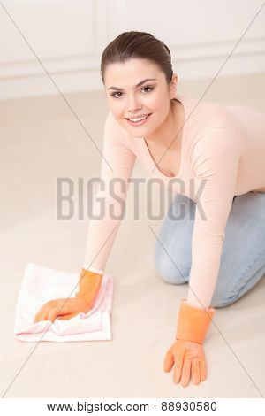 Woman washes floor on her knees