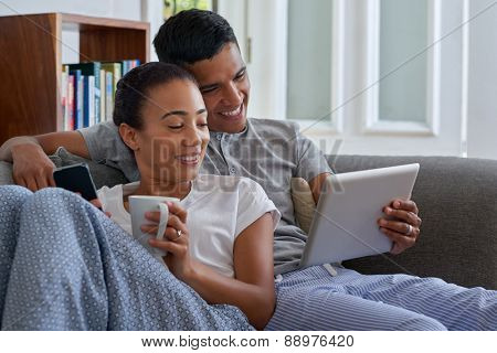 smiling couple with tablet computer on sofa couch at home