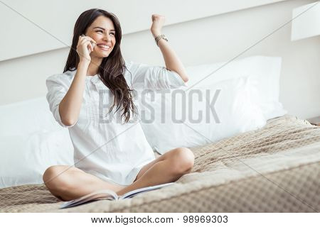 Beautiful Woman In A Shirt Talking On The Phone And Reading On A Bed