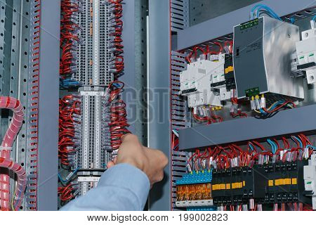 Photo of male electrical technician specialist checking indoor electric low-voltage cabinet equipment