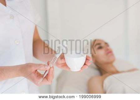 Cosmetologist hands preparing cleansing mask. Close-up shot of jar with facial beauty cream.