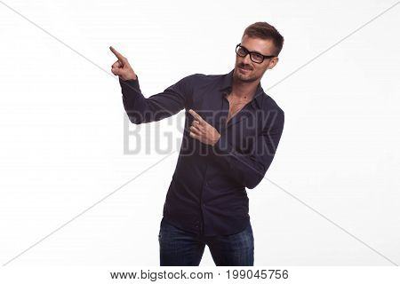 Young jocular man portrait of a confident businessman showing by hands on a gray background. Ideal for banners, registration forms, presentation, landings, presenting concept.