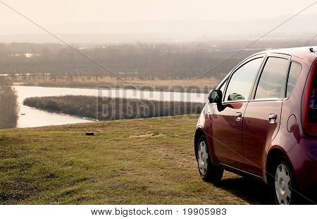 Pink Car On A High Bank Of The River At Sunset
