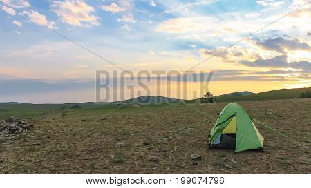 Tourist tent on the background of a sunset on a warm summer day outdoors
