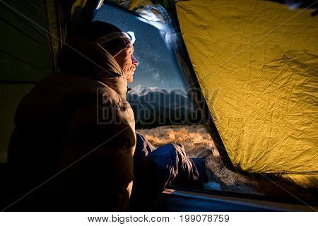 View From Inside A Tent On The Male Hiker Have A Rest In His Camping At Night. Man With A Headlamp S
