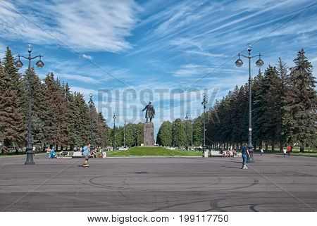 SAINT - PETERSBURG, RUSSIA - AUGUST 1, 2017: People rest and skate on The Krestovsky Island near Sergei Kirov Statue. On the background is The Maritime Victory Park