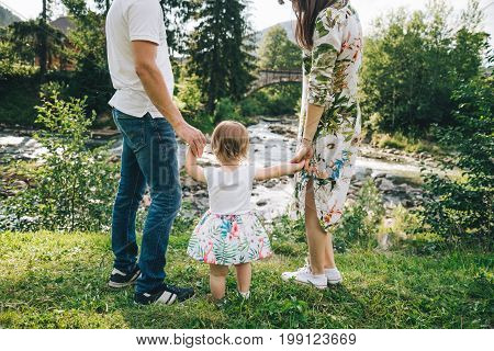 happy family play with daughter near the river in mountains, old bridge on backgeound