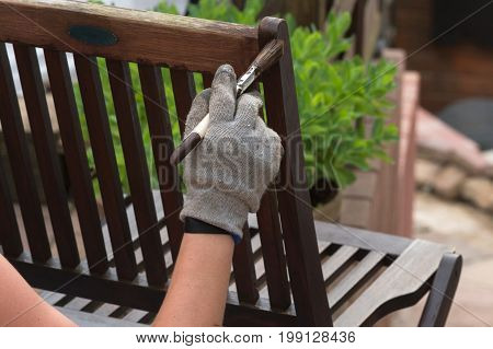 Painting and applying protective eco-friendly paint on a wooden garden chair.