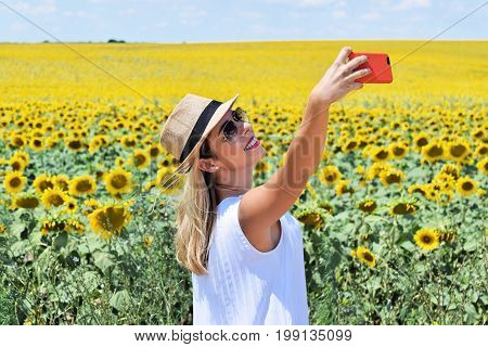 Smiling girl taking selfie in a sunflower field
