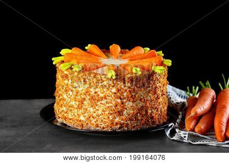 Plate with delicious carrot cake on black background