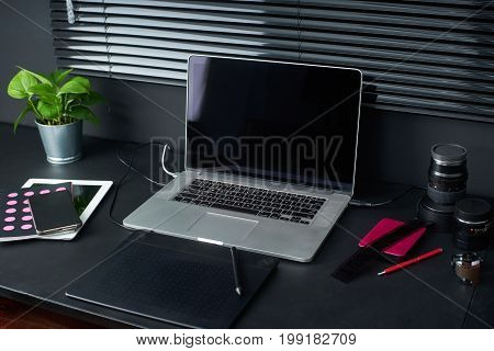 Work space on black table of a photographer or designer with laptop retro camera Stylish home studio concept of hipster . Seleted focus.