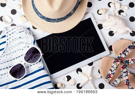 Summer women's accessories: sunglasses hat sandals shirt and tablet on creative background. Vacations travel and freelance work concept