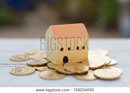 House And Golden Coins On Wooden Table With Blurred Backgroundproperties Concept