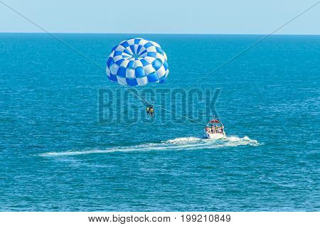 Blue Parasail Wing Pulled By A Boat In The Sea Water, Parasailing Also Known As Parascending Or Para
