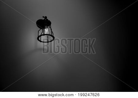 Wall lamp with black and white shade on cement wall.