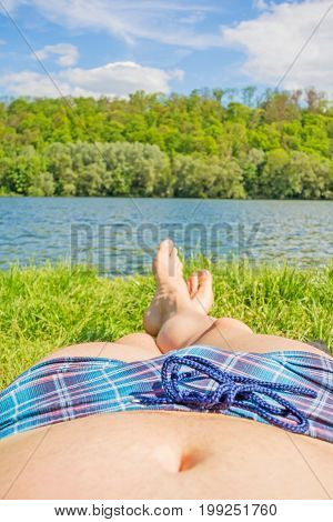 Man With Checkered Bathing Slip And Bare Feet At Lake / River, Meadow / Grass