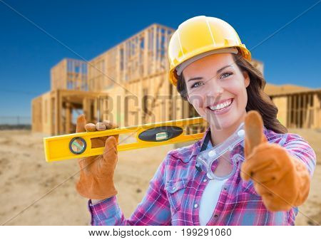 Female Construction Worker with Thumbs Up Holding Level Wearing Gloves, Hard Hat and Protective Goggles at Construction Site.