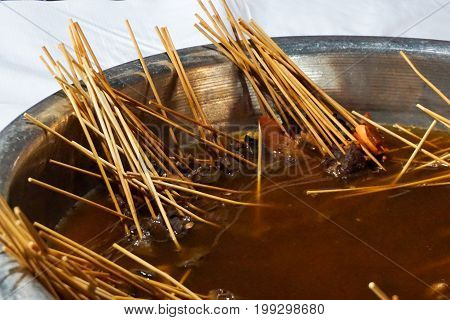 Moo Jum - small Pork and squid with wood stick in hot pot at Night market Thailand