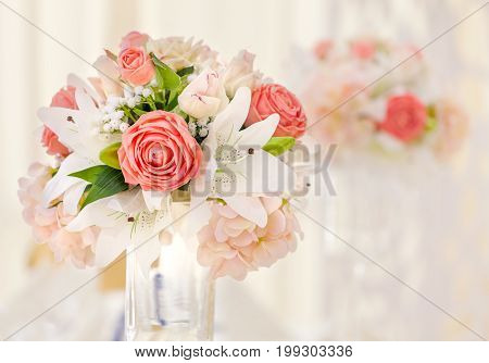 Served table for event dinner decorated with floral compositions in vases in pink and coral shades. Wedding bouquet