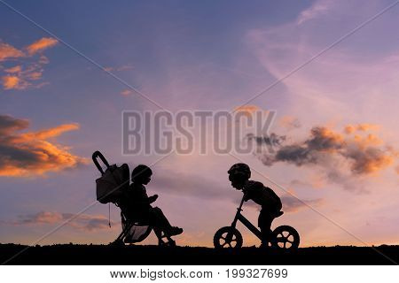 Silhouette of happy family, Little boy with small child in the stroller walking on road. my son