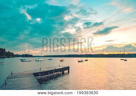 Summer afternoon landscape. Wooden pier and boat on the water at sunset.