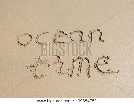ocean time words written into sand on beach