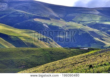 View of a green mountain range, part of the Ecuadorian Andes, with a beautiful sunny and cloudy sky. Cayambe, Ecuador.