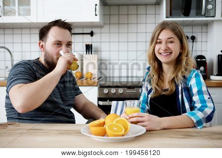 Young people drinking orange juice in kitchen.